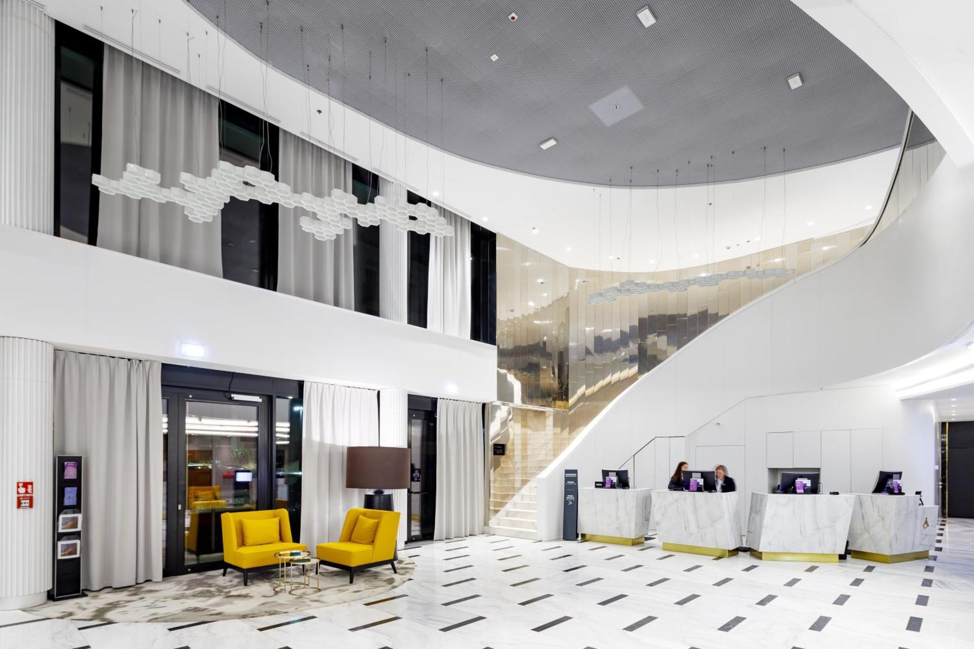 Radisson Blu Resort Świnoujście Exterior foto The photo shows a modern interior space, likely a hotel or a lobby area. It features a spacious, open design with high ceilings and a stylish staircase that leads to an upper level. The walls are mostly white, with large windows allowing natural ligh