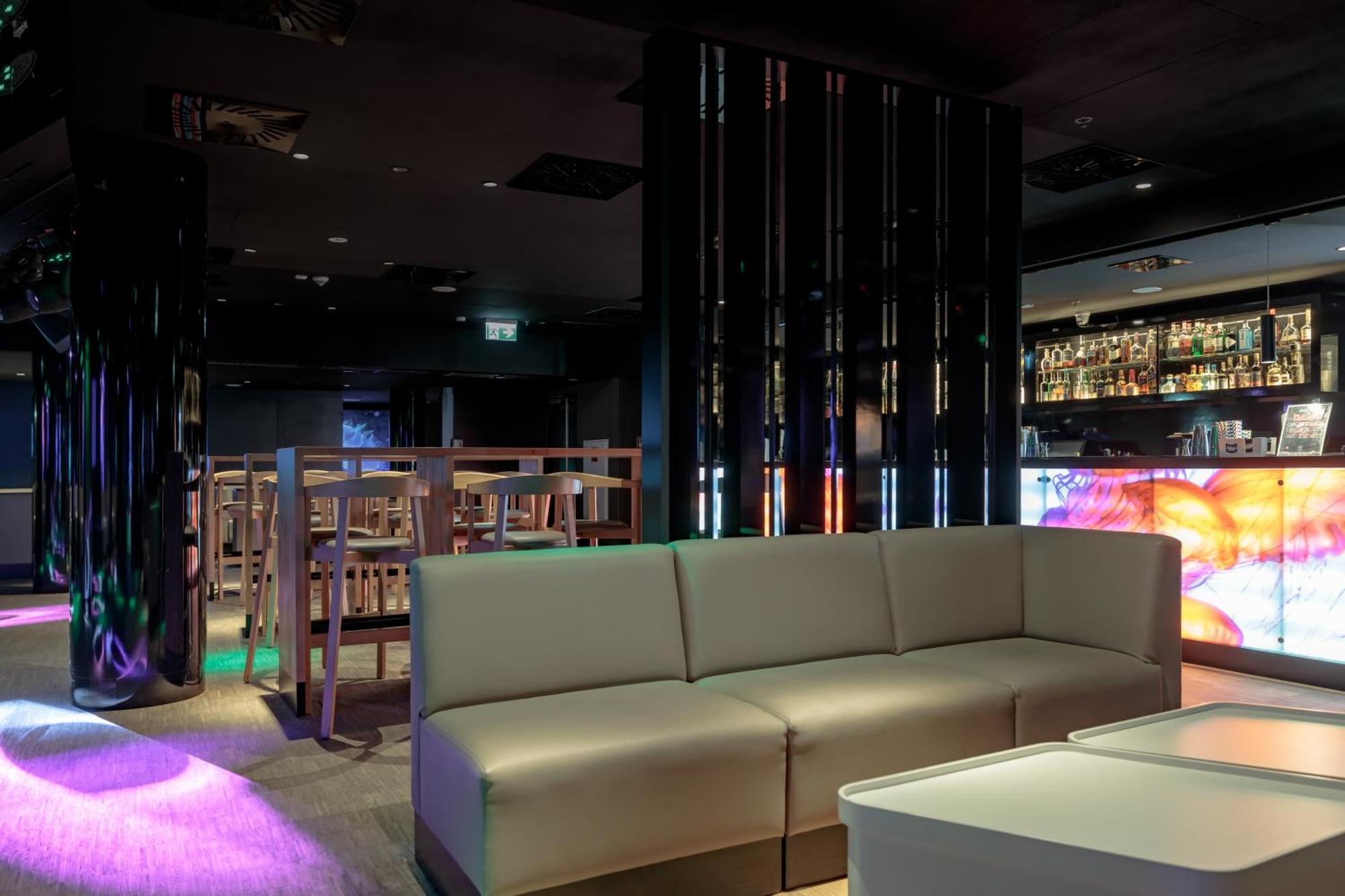 Radisson Blu Resort Świnoujście Exterior foto The photo shows the interior of a stylish lounge or bar. The space features a modern design with dark walls and a sleek atmosphere. There is a beige sectional sofa in the foreground, providing a casual seating area. In the background, a bar is visibl