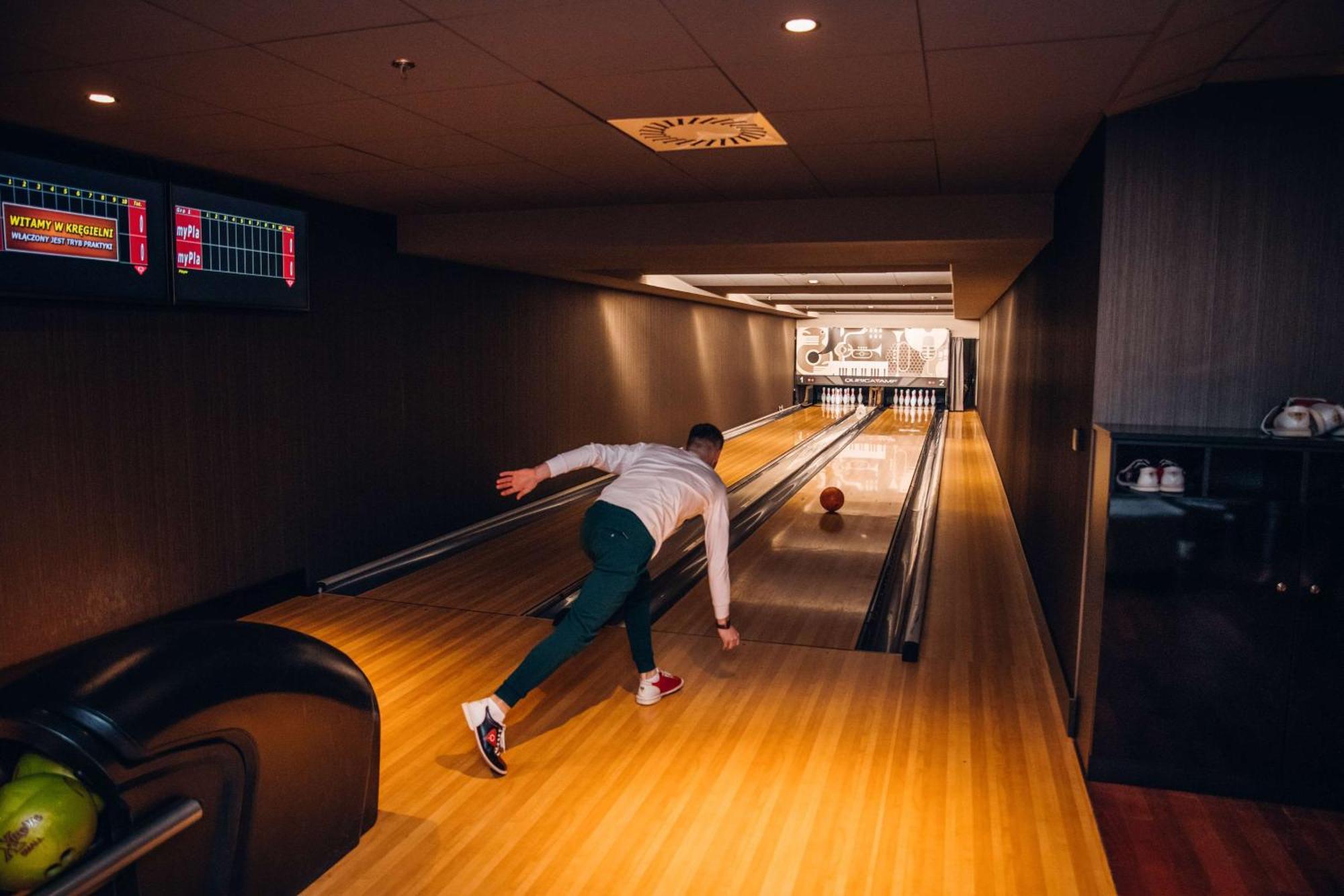 Radisson Blu Resort Świnoujście Exterior foto The photo shows a bowling alley. In the foreground, a person is throwing a bowling ball down the lane. They are wearing a white top and green pants, with red and white shoes. The bowling lane is made of polished wood, and at the end of the lane, ther