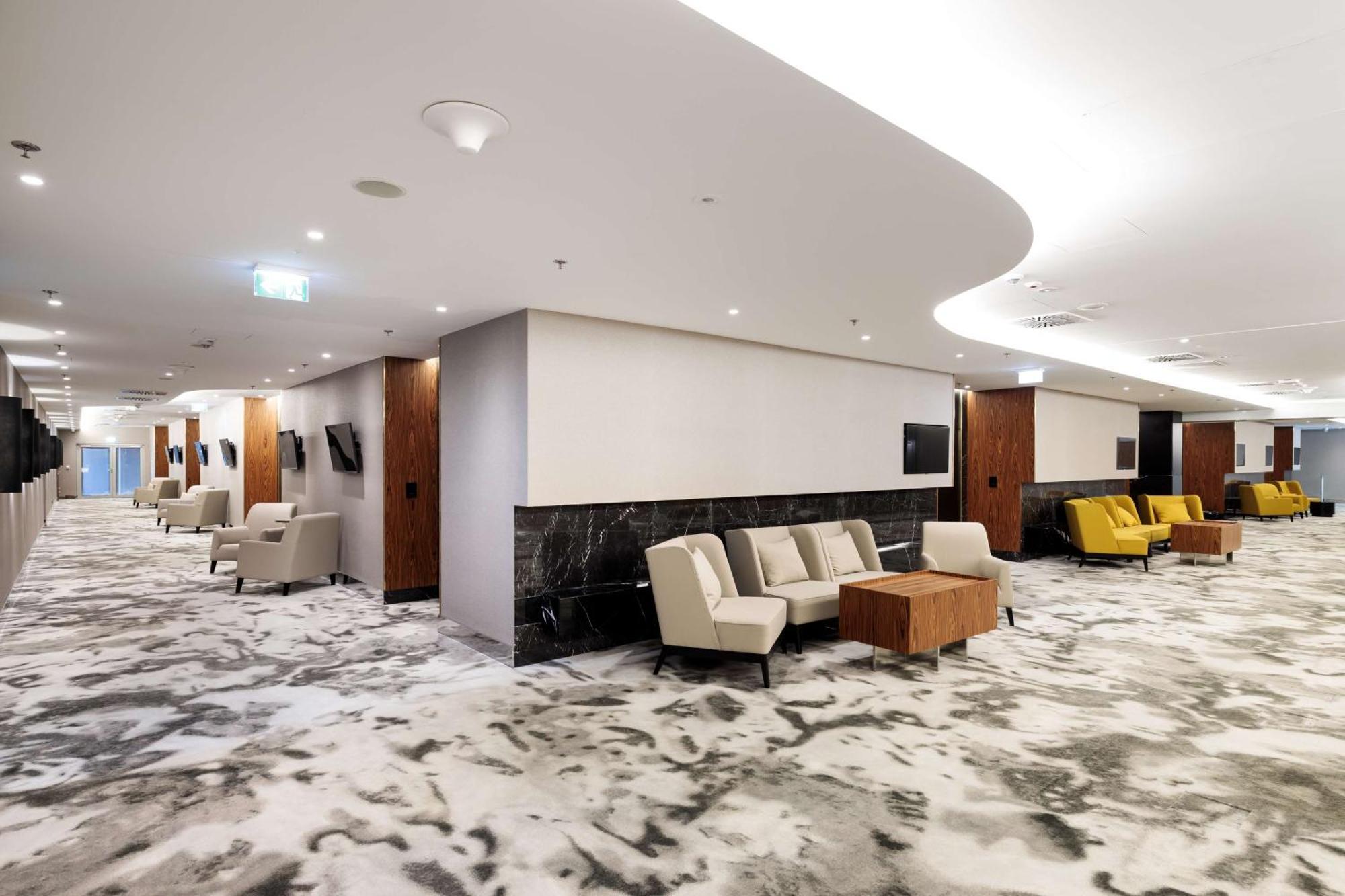 Radisson Blu Resort Świnoujście Exterior foto The photo shows a modern interior space, likely a lobby or lounge area. The flooring features a patterned carpet, and the walls are neutral in color, creating a calm ambiance. There are comfortable seating arrangements, including a group of beige cha