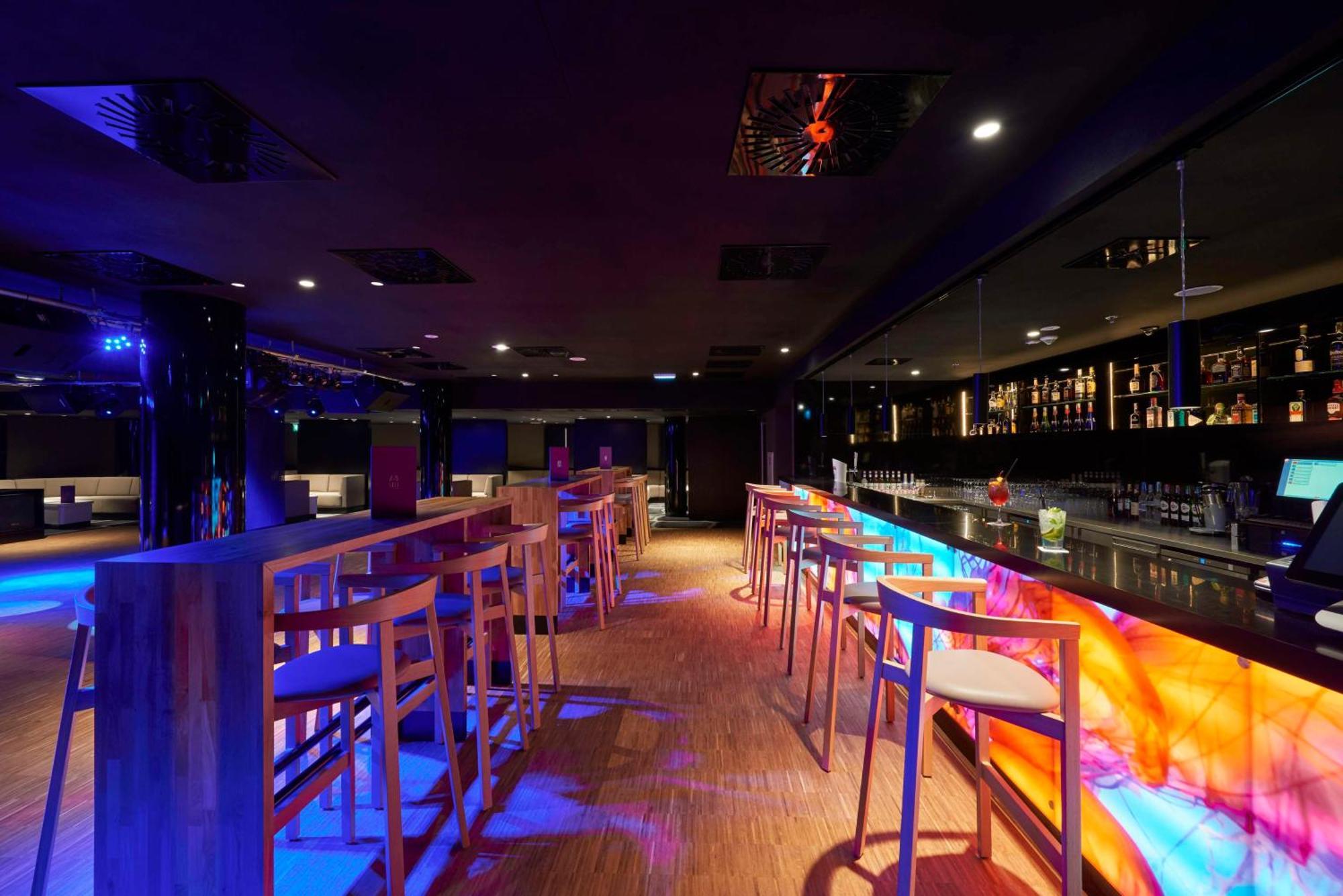 Radisson Blu Resort Świnoujście Exterior foto The photo depicts a modern bar interior with a sleek and contemporary design. There are high wooden stools positioned along a bar counter, which features vibrant, colorful lighting underneath. The bar area is dimly lit, creating a nightlife ambiance,