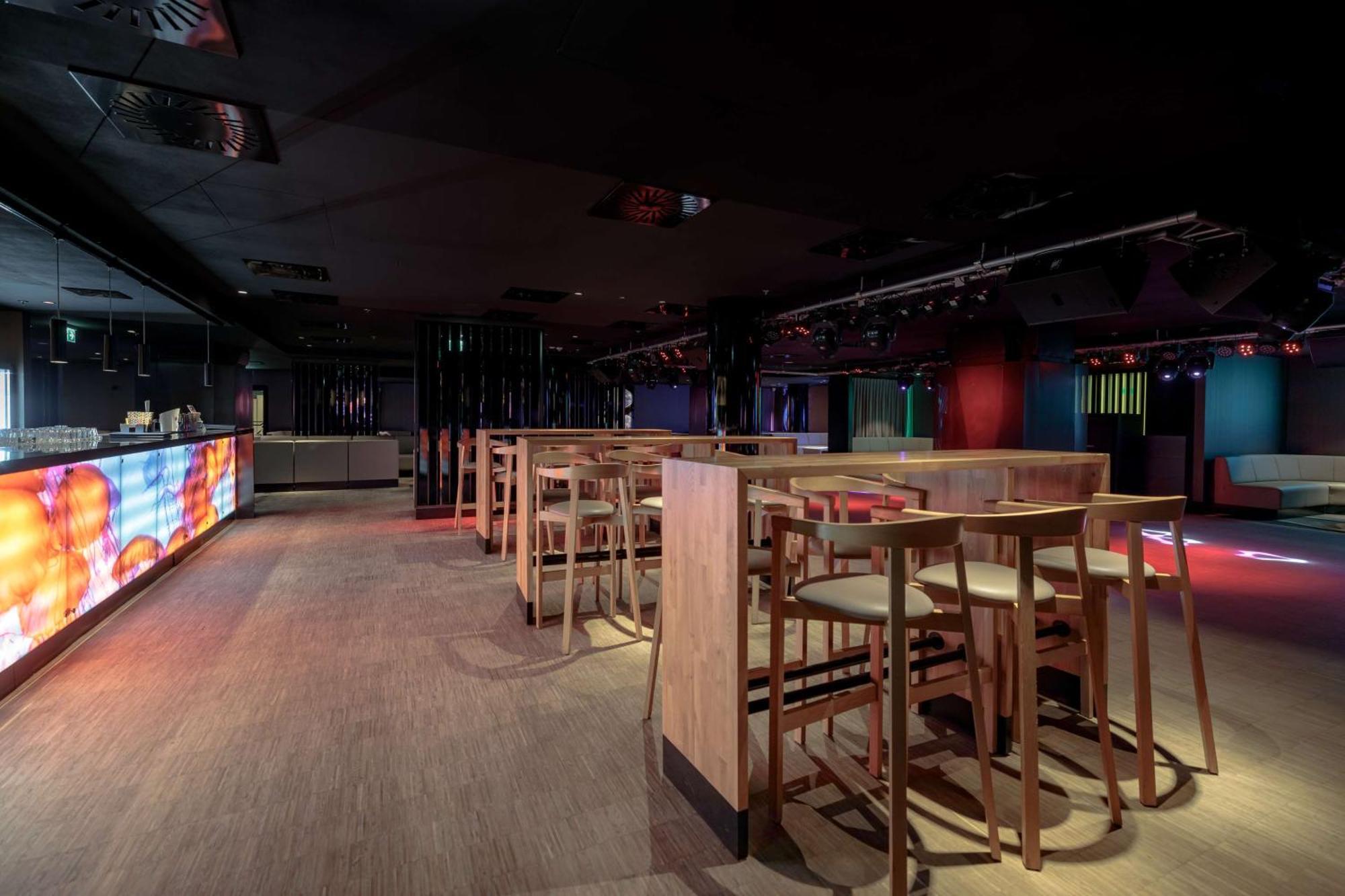 Radisson Blu Resort Świnoujście Exterior foto The photo shows an interior space that appears to be a bar or lounge. It features a modern design with a dark color scheme. There are several wooden high-top tables with matching stools arranged in the area. In the background, there is a bar counter,