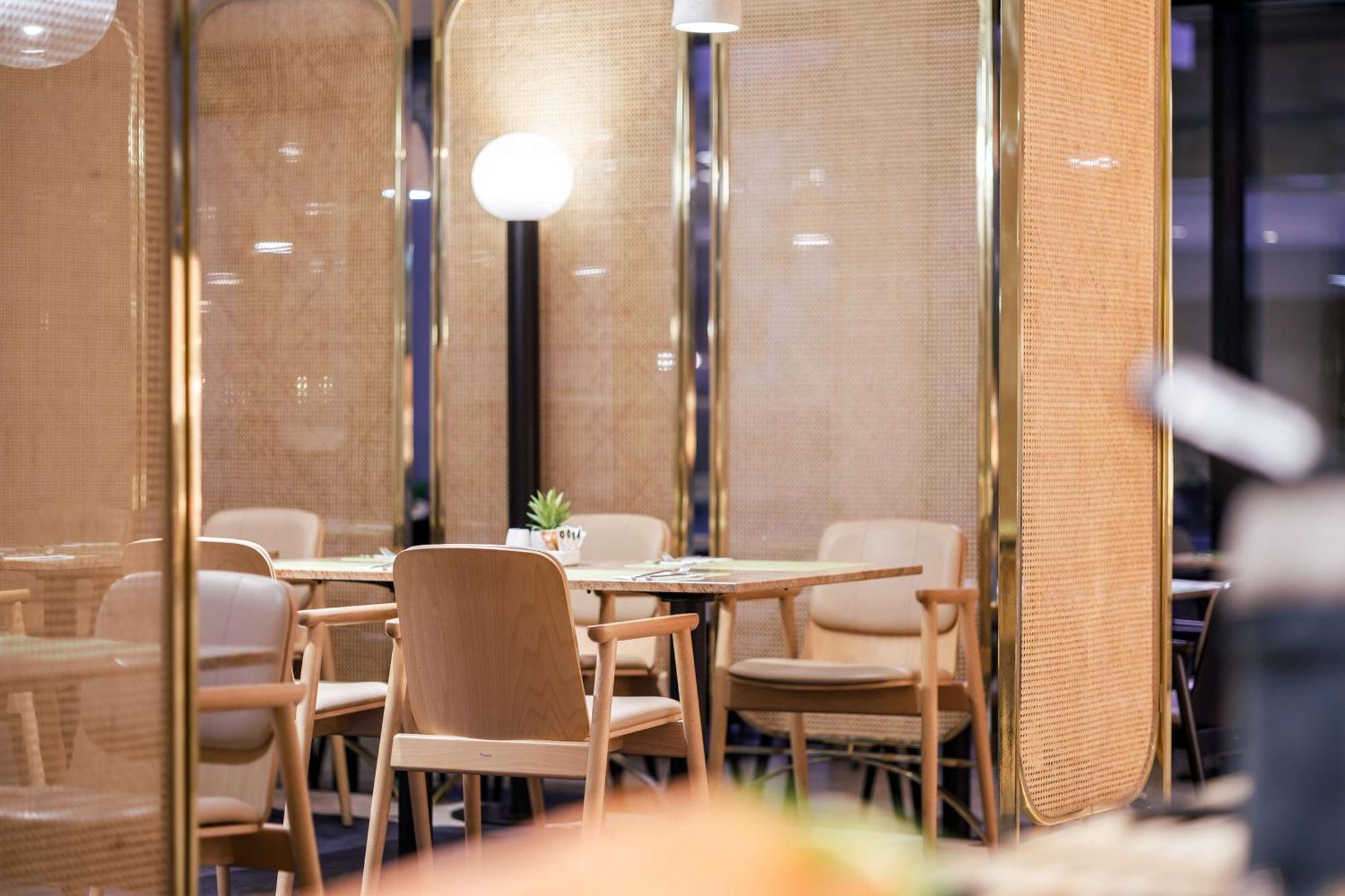 Radisson Blu Resort Świnoujście Exterior foto The image shows an interior space, likely part of a restaurant or café. There are several wooden chairs arranged around tables, and the overall decor features soft lighting and warm colors. The walls appear to be partially covered with a woven materi