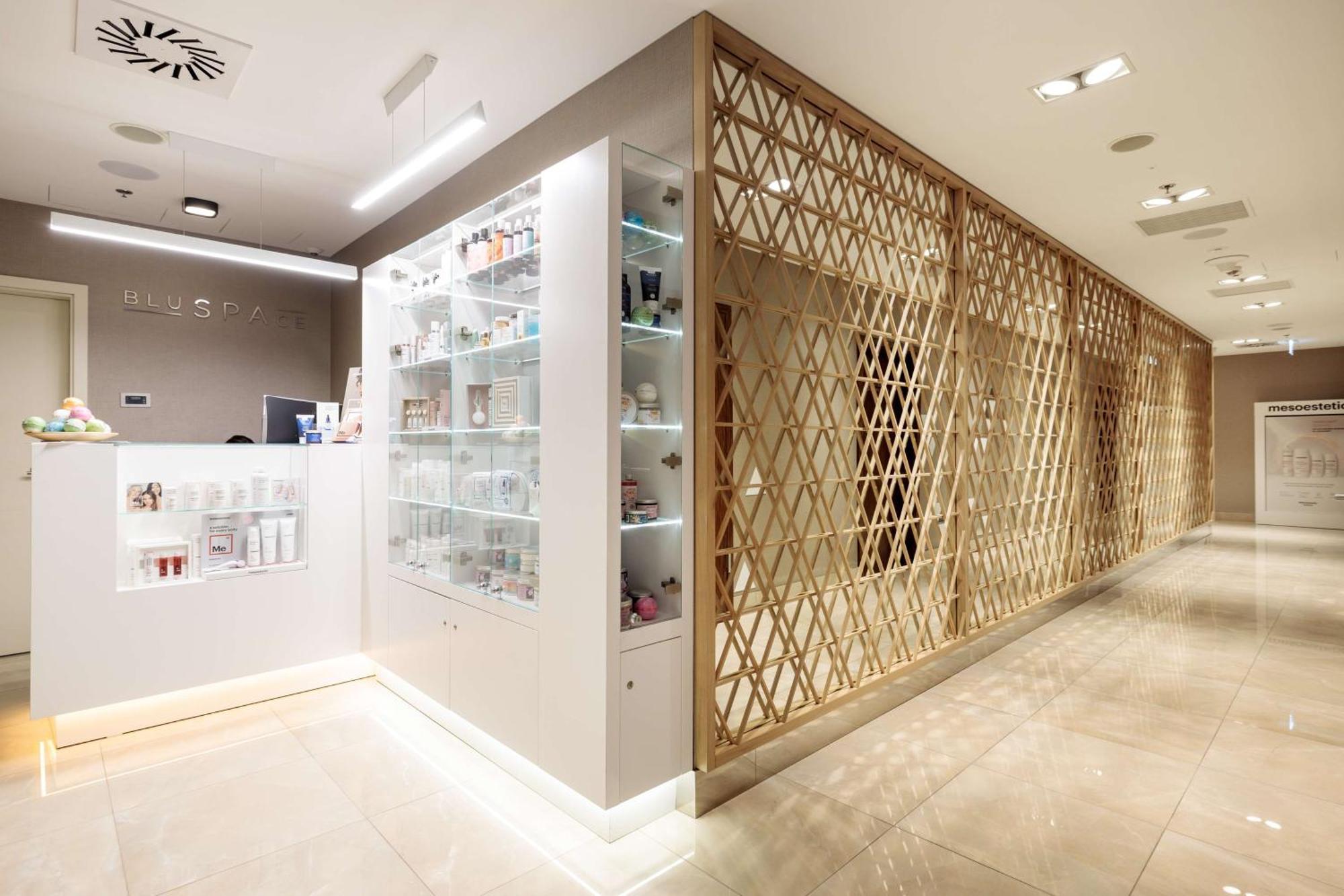 Radisson Blu Resort Świnoujście Exterior foto The photo shows a modern interior, likely from a spa or skincare clinic. On the left, there is a reception area with a sleek white counter and an illuminated display showcasing various skincare products. The wall behind the reception features a glass