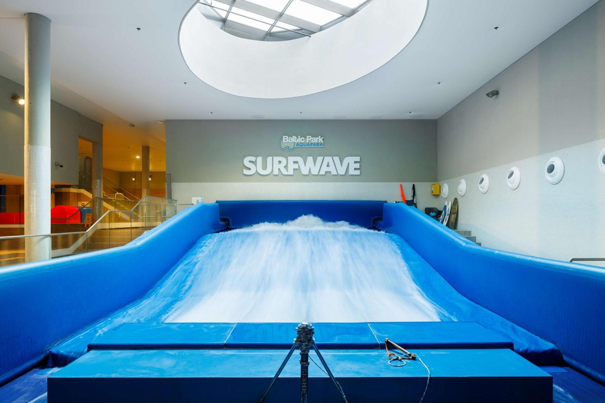 Radisson Blu Resort Świnoujście Exterior foto The photo shows an indoor surfing attraction called "Surfwave." It features a large blue ramp with water flowing down it, creating a wave-like effect for surfing. Above the ramp, there is a sign that says "SURFWAVE." The area appears well-lit and mod